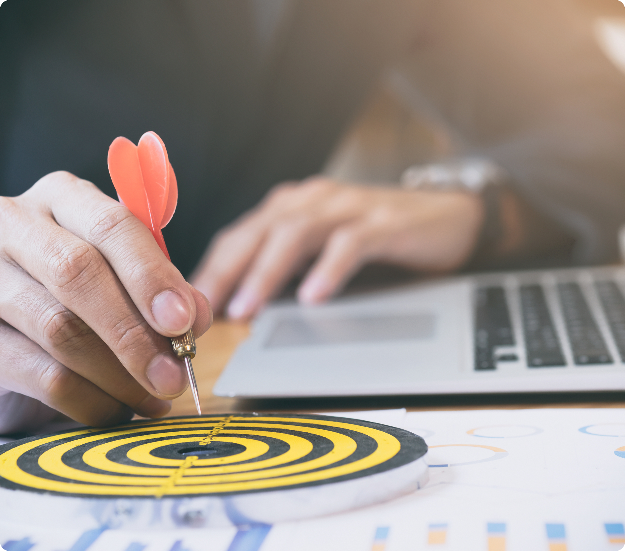 Hand with red dart hitting bullseye target representing strategic focus