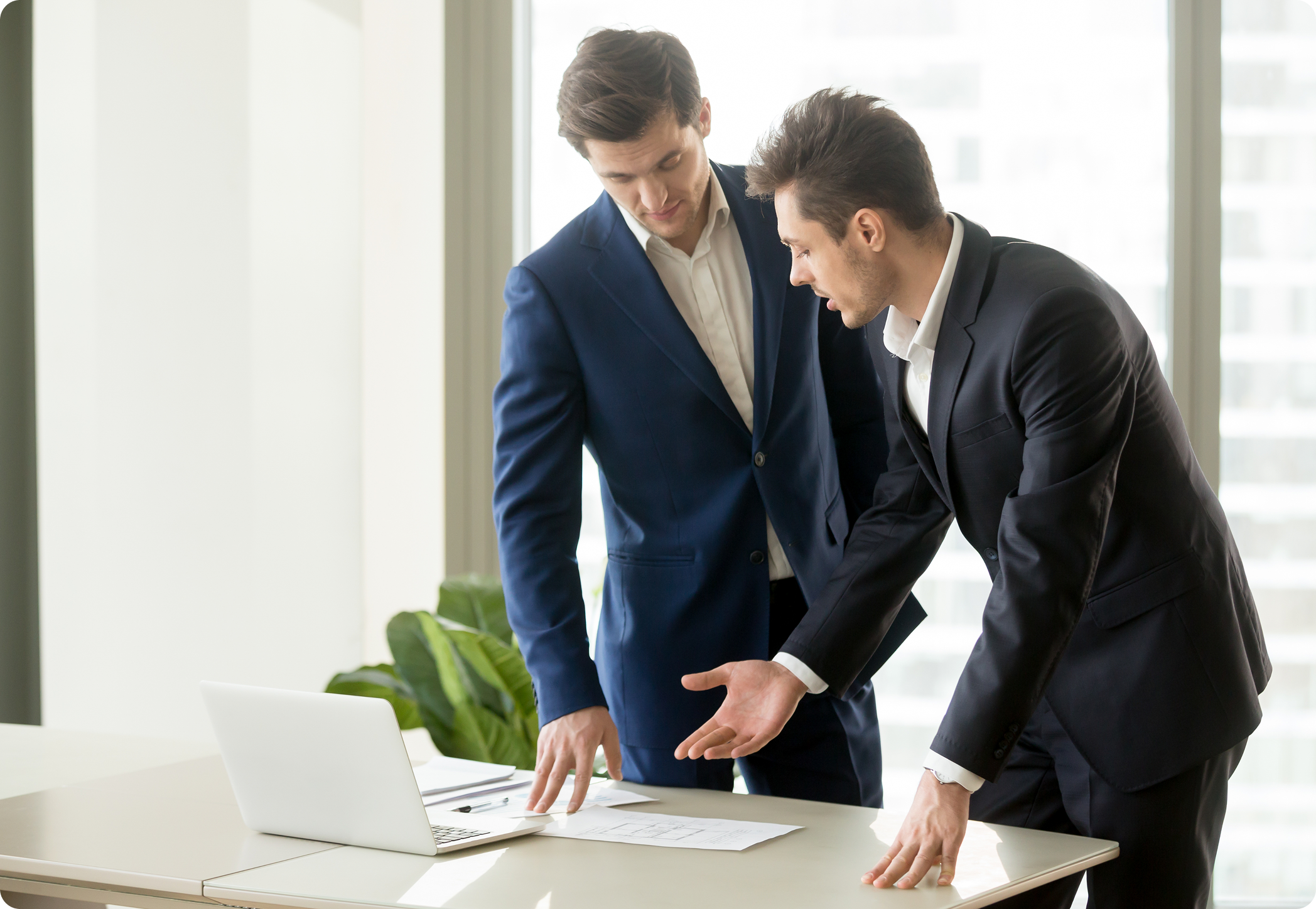 Two businessmen reviewing startup plans and documents on laptop